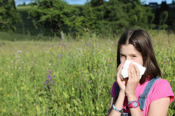 young caucasian girl blowing her nose for cold due to pollen allergy in spring - Photo, Image