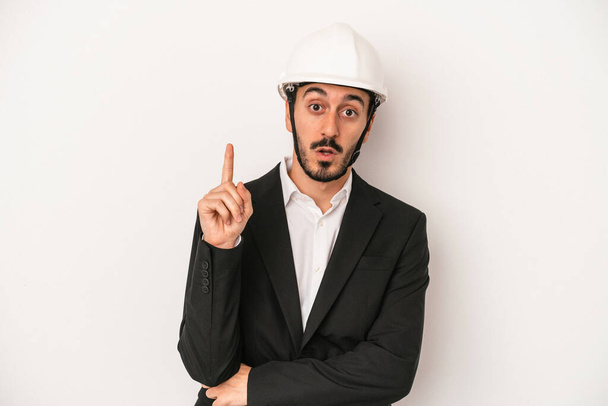 Young architect man wearing a construction helmet isolated on white background having some great idea, concept of creativity. - Foto, Imagem
