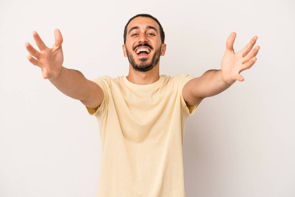 Young caucasian man isolated on white background feels confident giving a hug to the camera. - 写真・画像