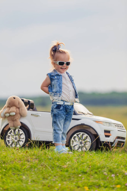 girl in sunglasses stands in front of a car - Fotó, kép