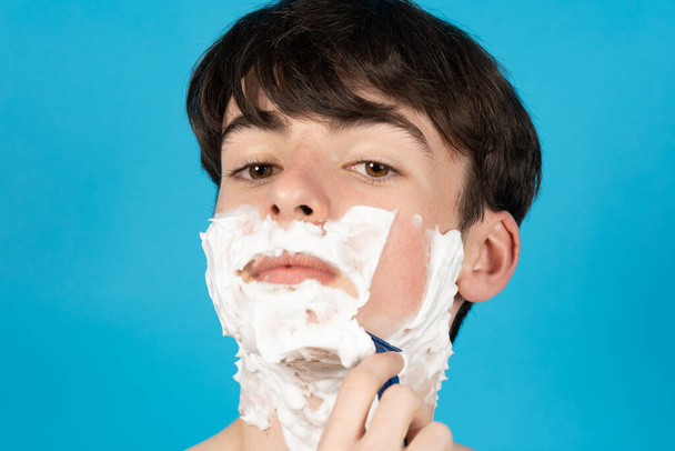 Nahaufnahme Porträt eines Teenagers, der sich zum ersten Mal sein Gesicht rasiert. - Foto, Bild