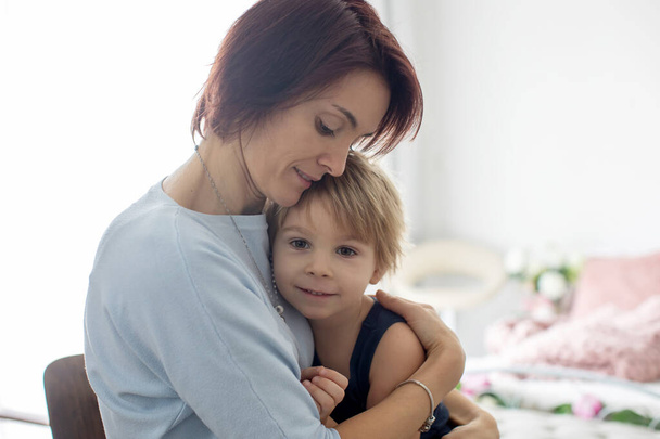 Portrait of mother and child, hugging on a back lit white background, enjoying family time together - Zdjęcie, obraz