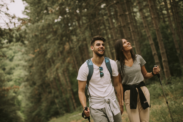 Пара молодых туристов с рюкзаками прогуливаются по лесу - Фото, изображение