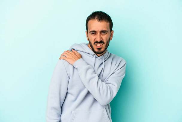Junger kaukasischer Mann isoliert auf blauem Hintergrund mit Schulterschmerzen. - Foto, Bild