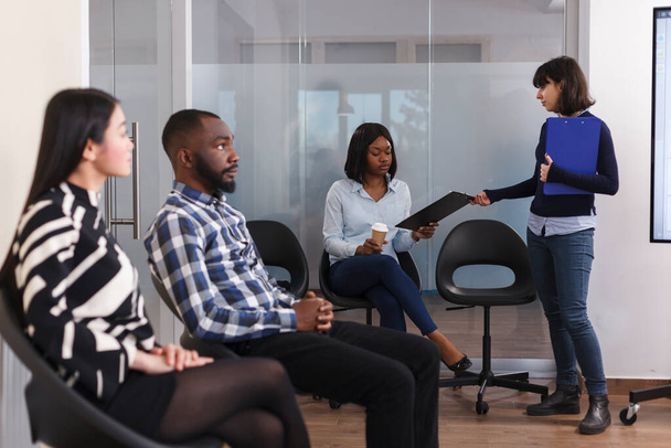 Personalabteilungsleiter gibt der afrikanisch-amerikanischen Frau ein Bewerbungsformular, während sie im Lobbybereich der Marketingfirma wartet. - Foto, Bild