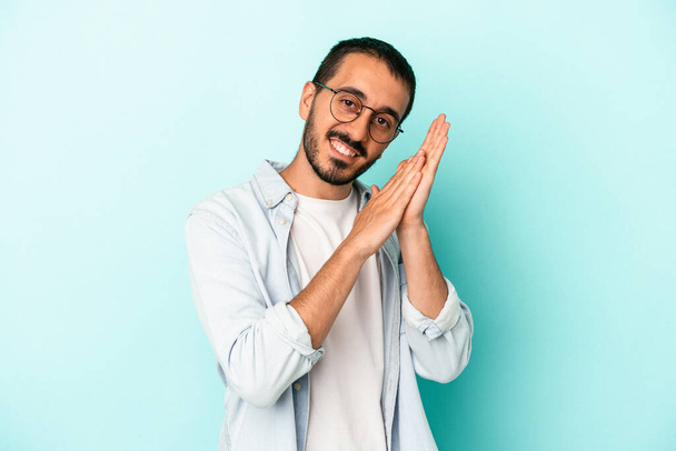 Young caucasian man isolated on blue background feeling energetic and comfortable, rubbing hands confident. - Photo, Image