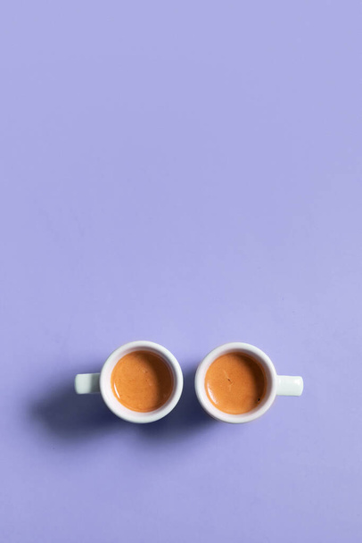 Two ceramic cups of espresso coffee. Top view. Minimalistic vertical stock photo in very peri color. - Foto, immagini