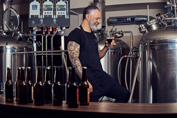 Älterer Brauer trinkt seine Produkte in Brauerei - Foto, Bild