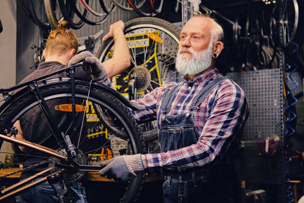 Büyükbaba ve torunu atölyede bisiklet tamir ediyorlar. - Fotoğraf, Görsel