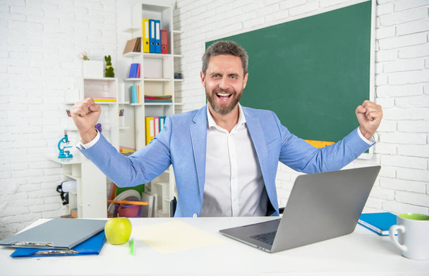 happy glad school teacher in classroom with computer at blackboard - Photo, Image