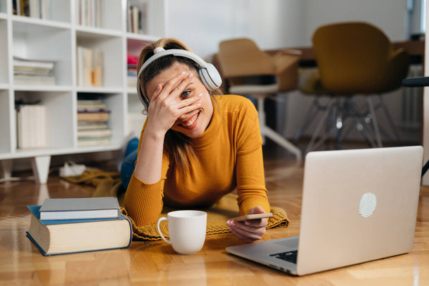 woman listening music on headphones and using laptop computer at home - Foto, Imagem