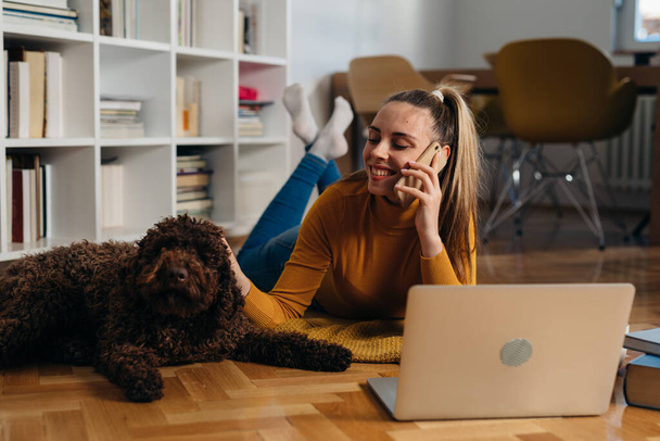 woman at home enjoying time with her dog and using laptop computer - Foto, immagini
