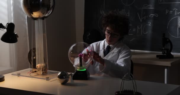 Az iskolás fiú fizika órán kísérletezik. Fiatal diák csinál fizika kísérlet az osztályteremben - Felvétel, videó