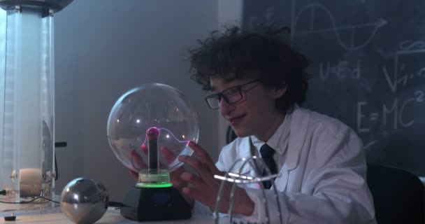 Az iskolás fiú fizika órán kísérletezik. Fiatal diák csinál fizika kísérlet az osztályteremben. - Felvétel, videó