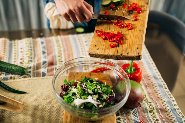 close up man cutting red paprika for salad - Foto, Bild