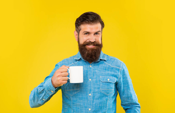 Happy caucasian man holding tea mug yellow background - Photo, image