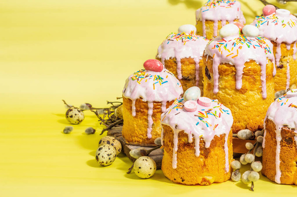 Traditional Easter cake. Festive sweet food with icing and decor. Eggs, nest, willow, trendy hard light, dark shadow. Traditional baking on bright yellow background, copy space - Photo, Image