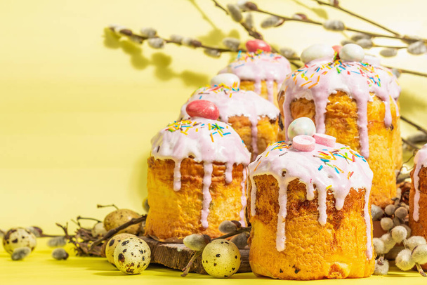 Traditional Easter cake. Festive sweet food with icing and decor. Eggs, nest, willow, trendy hard light, dark shadow. Traditional baking on bright yellow background, copy space - Fotografie, Obrázek