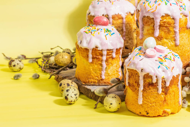 Traditional Easter cake. Festive sweet food with icing and decor. Eggs, nest, willow, trendy hard light, dark shadow. Traditional baking on bright yellow background, close up - Foto, Bild