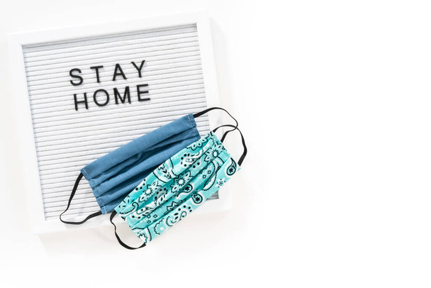 STAY HOME sign on message board with a homemade face mask. - Photo, Image