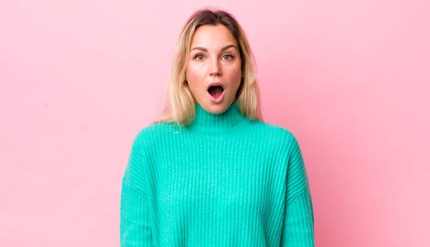 pretty blonde woman looking very shocked or surprised, staring with open mouth saying wow - Foto, imagen