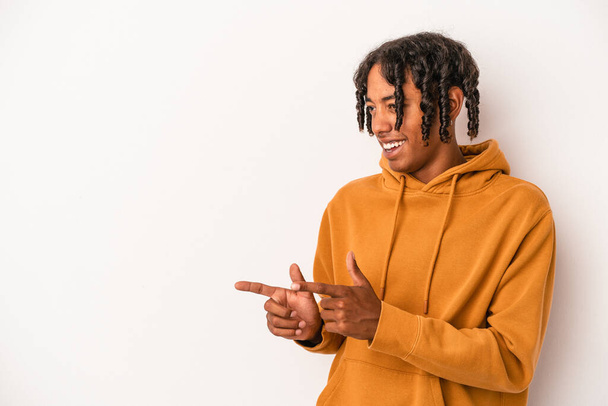 Junger afrikanisch-amerikanischer Mann isoliert auf weißem Hintergrund zeigt mit dem Daumenfinger weg, lacht und unbeschwert. - Foto, Bild