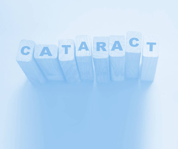 Katarakt-Wort aus Bausteinen auf hellem Cyan. Konzept zur Augengesundheit - Foto, Bild