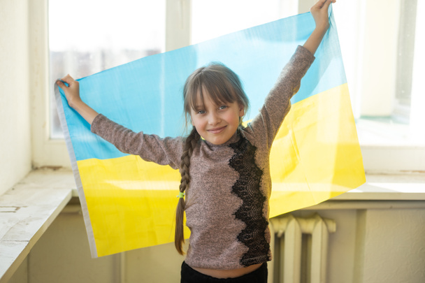 Dziewczynka pokryta ukraińską flagą. Koncepcja stania z narodem ukraińskim w stanie wojny z Rosją. - Zdjęcie, obraz