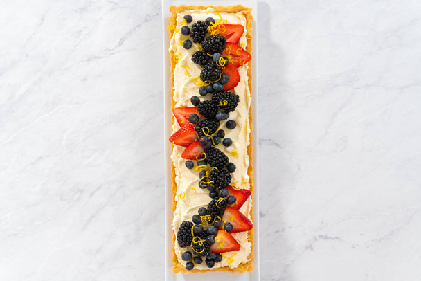 Flat lay. Freshly baked mascarpone tart with fresh berries and garnished with lemon zest. - Φωτογραφία, εικόνα