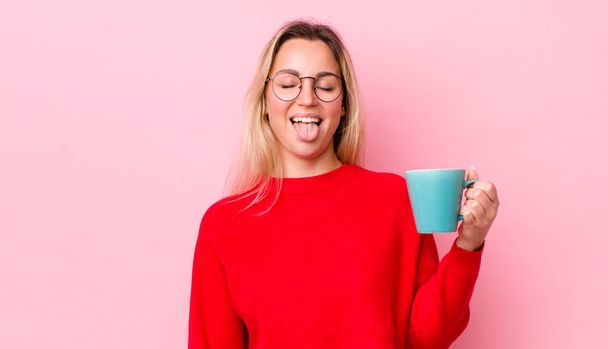 blonde pretty woman with cheerful and rebellious attitude, joking and sticking tongue out. coffee cup concept - Φωτογραφία, εικόνα