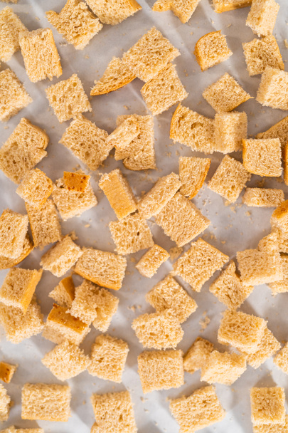 Baking croutons seasoned with olive oil and spiced on a baking sheet lined with parchment paper. - Photo, Image
