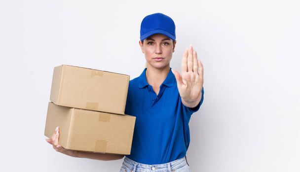 blonde pretty woman looking serious showing open palm making stop gesture. shipping boxes concept - Фото, зображення
