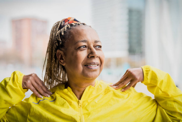 Mujer africana mayor haciendo ejercicios de calentamiento antes de correr en la ciudad - Adultos mayores Concepto de estilo de vida de las personas deportivas - Foto, Imagen