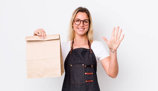 blonde pretty woman smiling and looking friendly, showing number five. delivery take away concept - Photo, Image