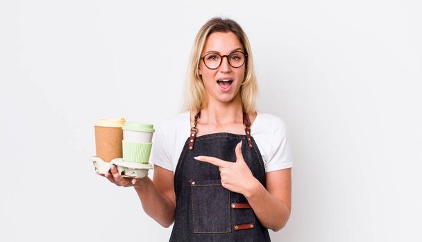 blonde pretty woman looking excited and surprised pointing to the side. take away coffee concept - Foto, imagen