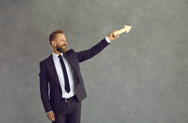 Happy businessman holding arrow going up as symbol of business growth and success - Foto, imagen