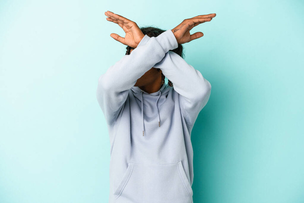 Young african american man isolated on blue background keeping two arms crossed, denial concept. - Foto, imagen