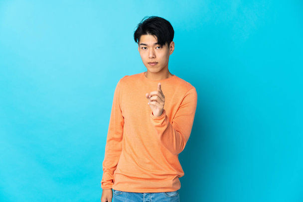 Young Chinese man isolated on blue background frustrated and pointing to the front - Foto, Bild