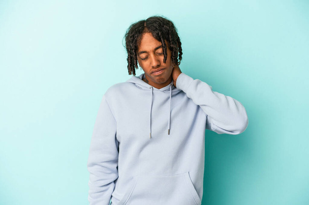 Junger afrikanisch-amerikanischer Mann isoliert auf blauem Hintergrund mit Nackenschmerzen aufgrund von Stress, massiert und berührt ihn mit der Hand. - Foto, Bild