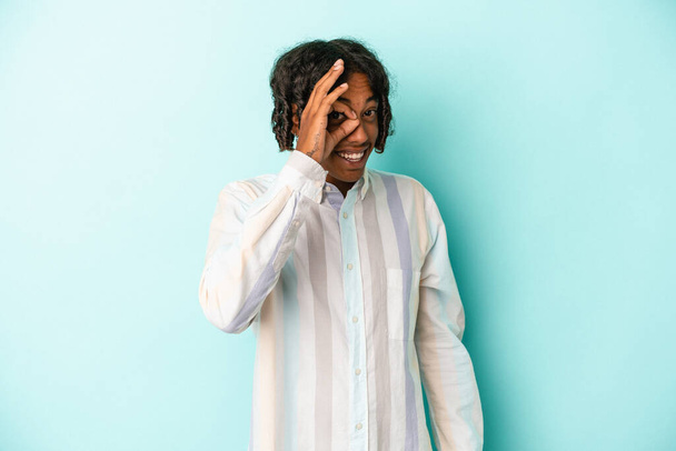 Young african american man isolated on blue background excited keeping ok gesture on eye. - Фото, изображение