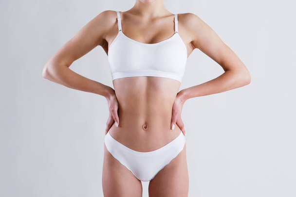 Close up shot of unrecognizable fit woman in lingerie isolated on white background. Torso of slim attractive female with flat belly in white underwear. Copy space for text. - Φωτογραφία, εικόνα