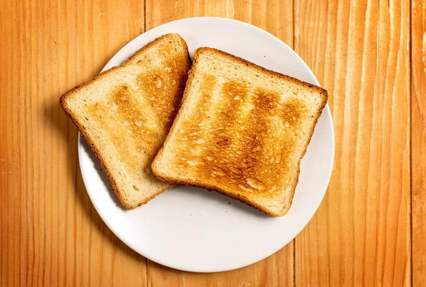 Twee sneetjes toast brood op een houten tafelopstelling - Foto, afbeelding