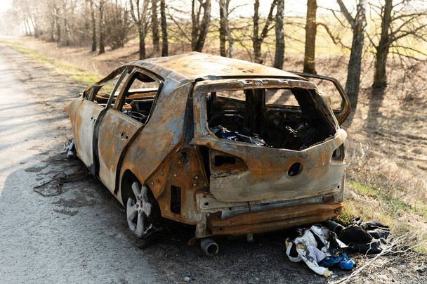 verbranntes Auto aus dem Krieg in der Ukraine. Autounfall auf der Straße. Ausgebranntes Auto am Straßenrand. Kaputter Transport. - Foto, Bild