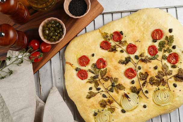 Floral painting focaccia, italian garden flatbread art with parsley, tomatoes, onions, sesame seeds and capers on light grey background - Foto, Bild