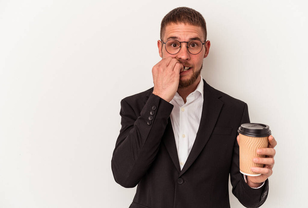 Молодий діловий кавказький чоловік тримає каву ізольовано на білому фоні кусаючи нігті, нервуючий і дуже тривожний
. - Фото, зображення