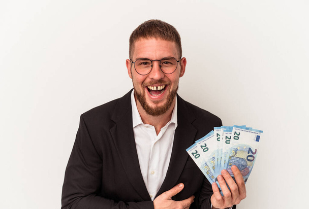 Junger kaukasischer Geschäftsmann mit Geldscheinen auf weißem Hintergrund, der lacht und Spaß hat. - Foto, Bild