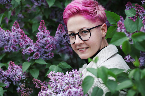 attractive young woman with pink lilac flowers on a purple background with a flowering branch of lilac - Foto, immagini