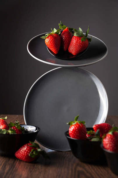 Auf dem Teller liegen Erdbeeren. Auf einem dunklen Hintergrund. Selektiver Fokus. - Foto, Bild