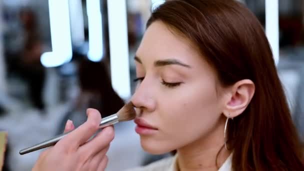 Beautiful brunette woman is dusted and toned with a brush in a beauty salon. - Filmagem, Vídeo
