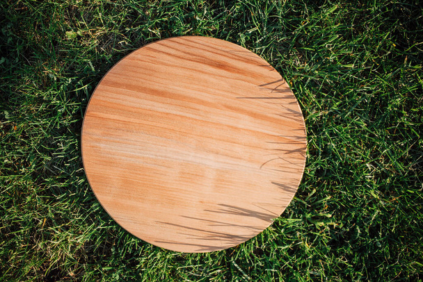 Tabla de cortar redonda de madera para cortar en hierba verde - Foto, imagen